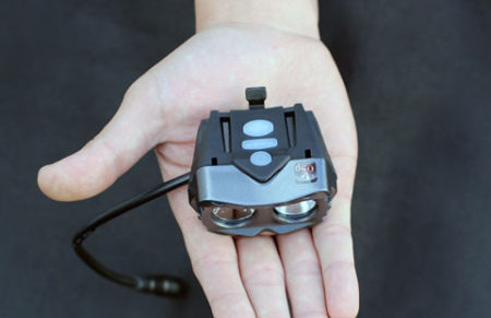 Compact dual lens Cygolite light powered by a lithium ion battery, held in an open hand